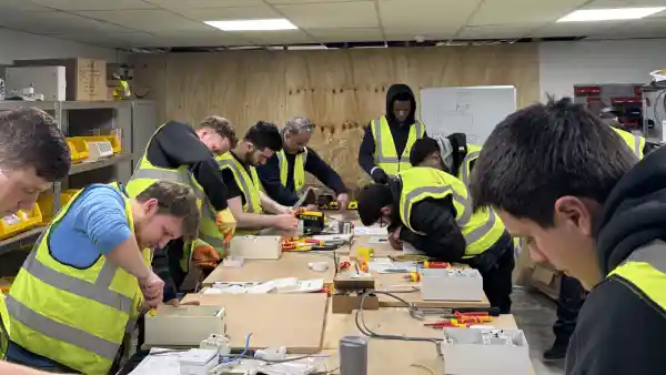 Electrical students in high-visibility vests working hands-on with tools and electrical components at Learn Trade Skills training centre.