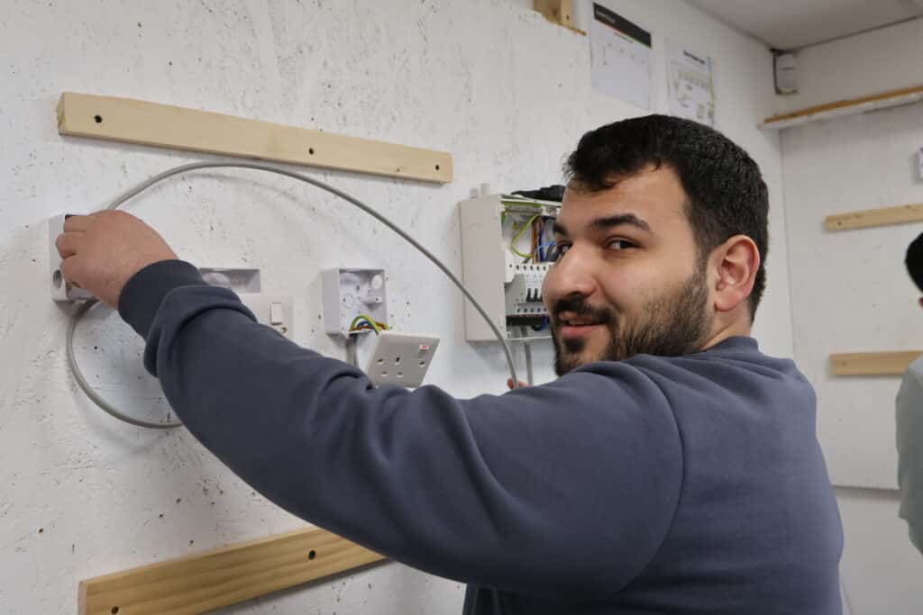 UK electrician qualification pathway showing Level 2, Level 3, NVQ Level 3 and AM2 requirements