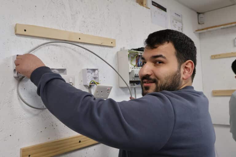 UK electrician qualification pathway showing Level 2, Level 3, NVQ Level 3 and AM2 requirements